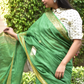 An aesthetic image of lady in Myrtle Linen Saree in Olive Green, womens workwear standing in a garden