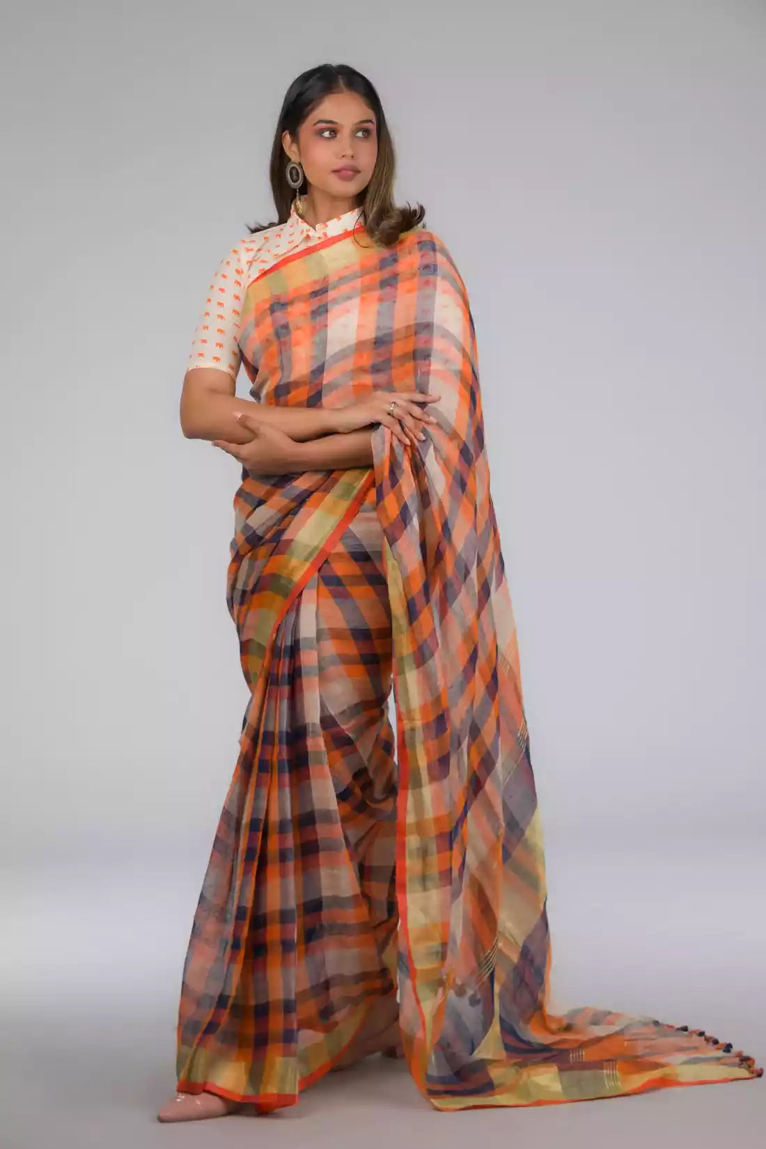 A lady in Linen By Linen Rustic Saree in Beige Checks, womens workwear standing against a grey background looking sideways
