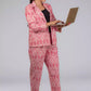 A lady in Pink Woven Ikkat bottom In Pure Cotton, womens workwear standing against a grey background using a laptop