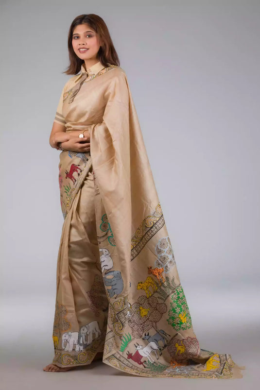 A model in Pure Tussar in Beige Saree adorned with Patachitra a womens workwear is standing against a grey background