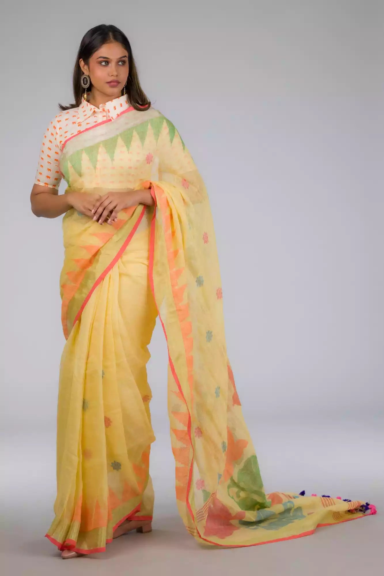 A lady in Jamdani hand weaving saree, womens workwear standing against a beige background looking sideways