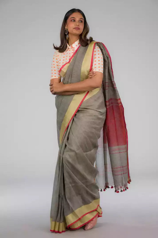 A model in Shades of Grey Linen Cotton with Orange Border Saree, a womens workwear is standing against a grey background