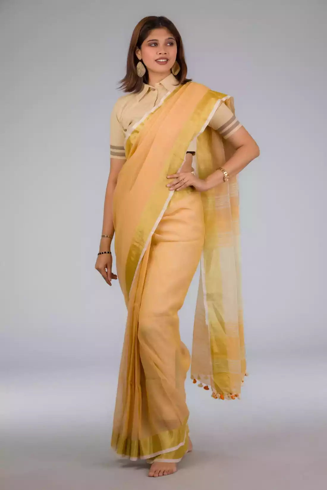 side look of a beautiful woman with short hair wearing beige saree with collared blouse