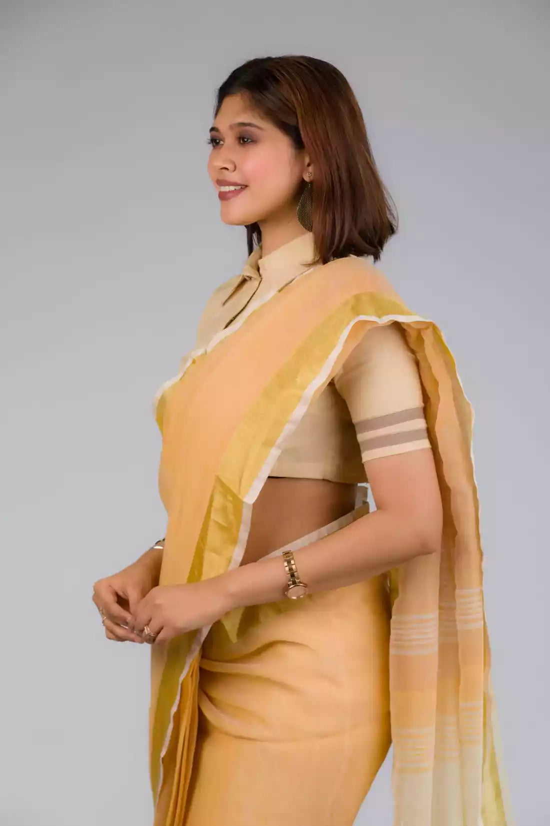 closure side look of a beautiful woman with short hair wearing beige saree with collared blouse