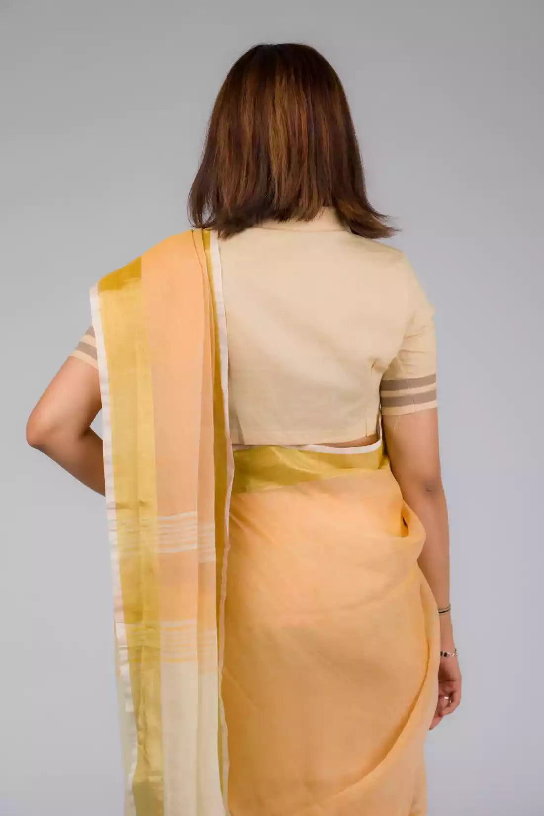 back look of a beautiful woman with short hair posing in beige saree with collared blouse