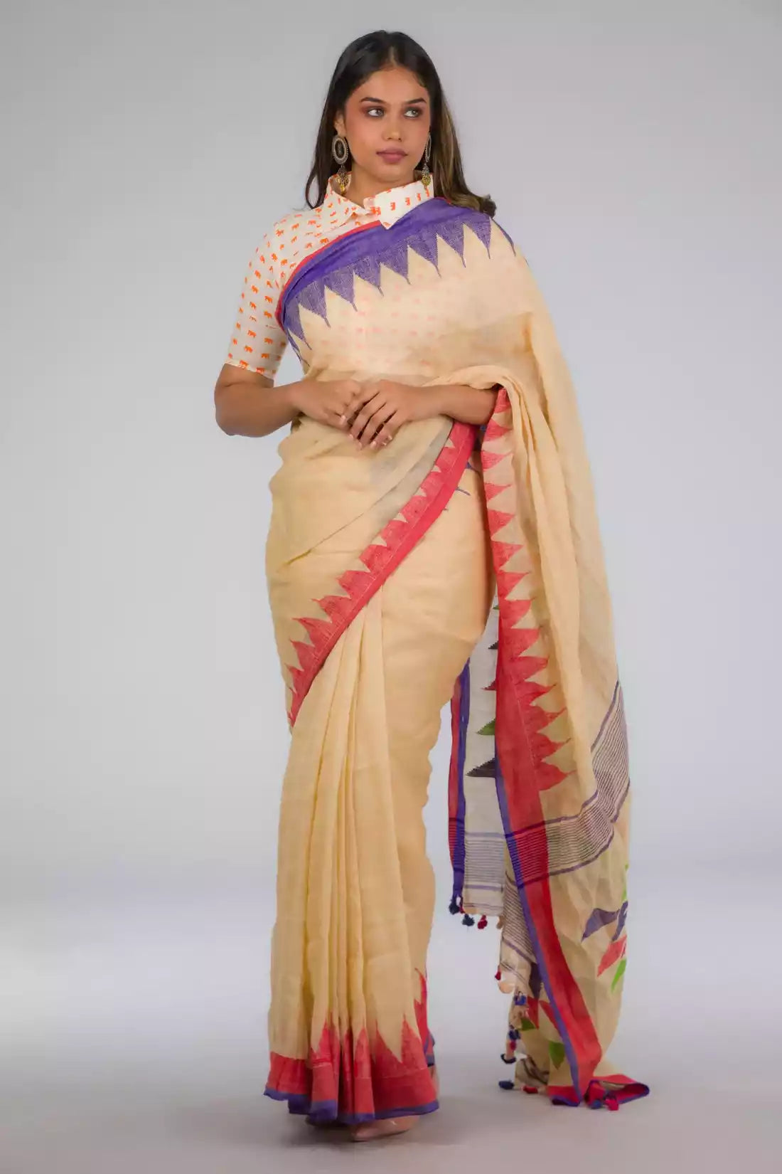 front view of a beautiful woman with short hair wearing beige saree with collared blouse and multicolor borders at both ends of the saree