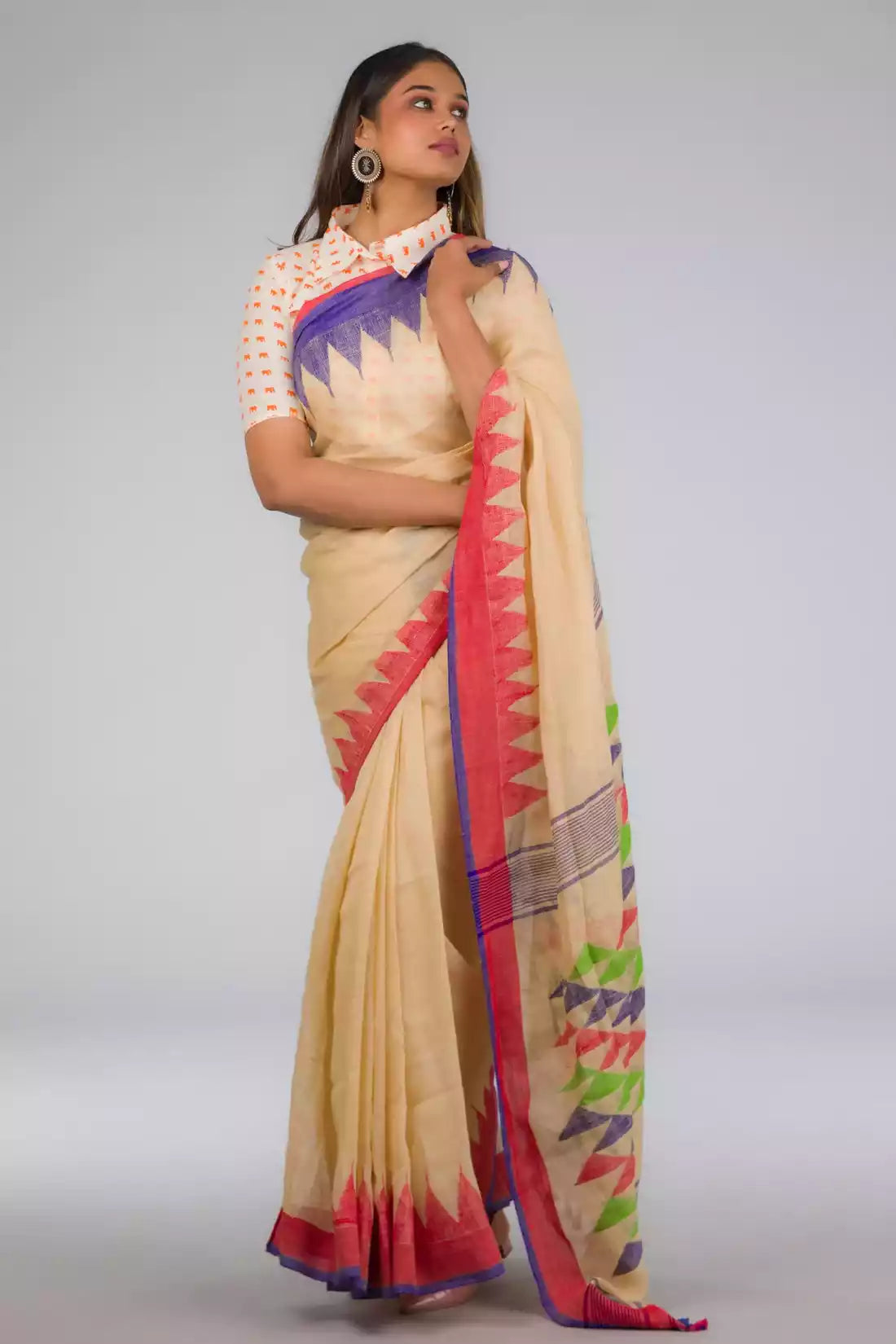 front view of a beautiful woman posing in beige saree with collared blouse and multicolor borders at both ends of the saree