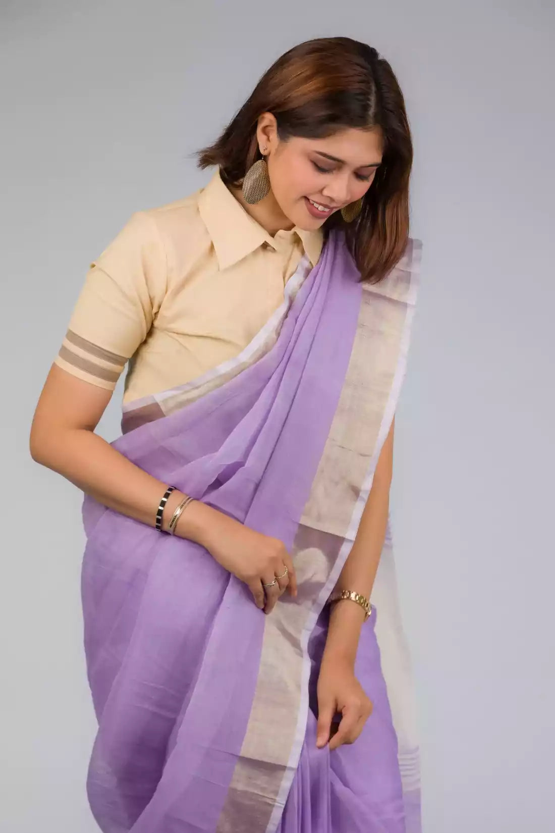 A lady in Lilac Blush Linen Saree, womens workwear standing against a grey background looking  down