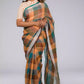 A model in Earthy Brown & Peacock Green Checkered Linen Saree, womens workwear standing against a grey background