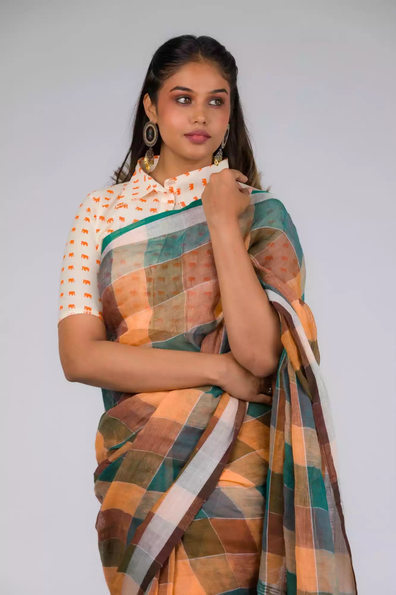 A zoomed in view of women wearing a Earthy Brown & Peacock Green Checkered Linen Saree, formal dress for women