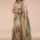 A model in Hand-painted Patachitra Lotus & Peacock design Pure Tussar Saree in Beige a womens workwear is standing  against a beige background