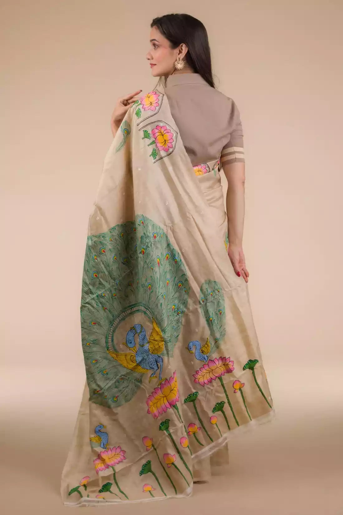 A zoomed out view of back of women wearing a Hand-painted Patachitra Lotus & Peacock design Pure Tussar Saree in Beige, formal dress for women