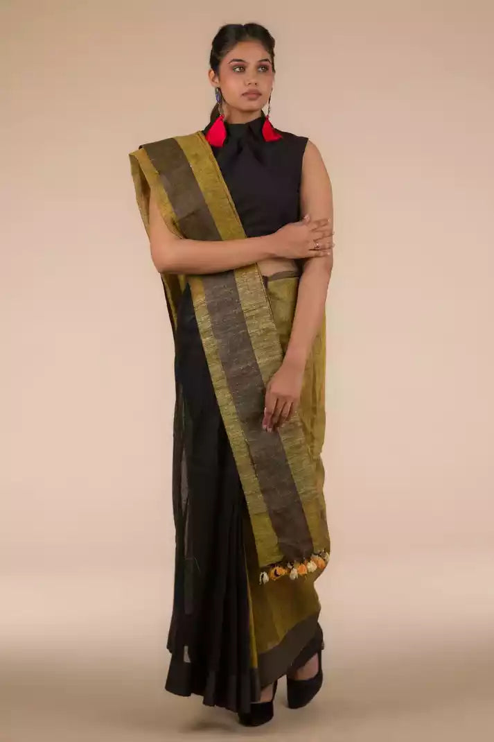 A model in Black Pure Linen Saree with Tints of Mustard a womens workwear is standing  against a beige background
