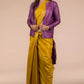 A lady in Mustard with purple border Plain In Pure Tussar with Ghicha Border Saree standing against a beige background.