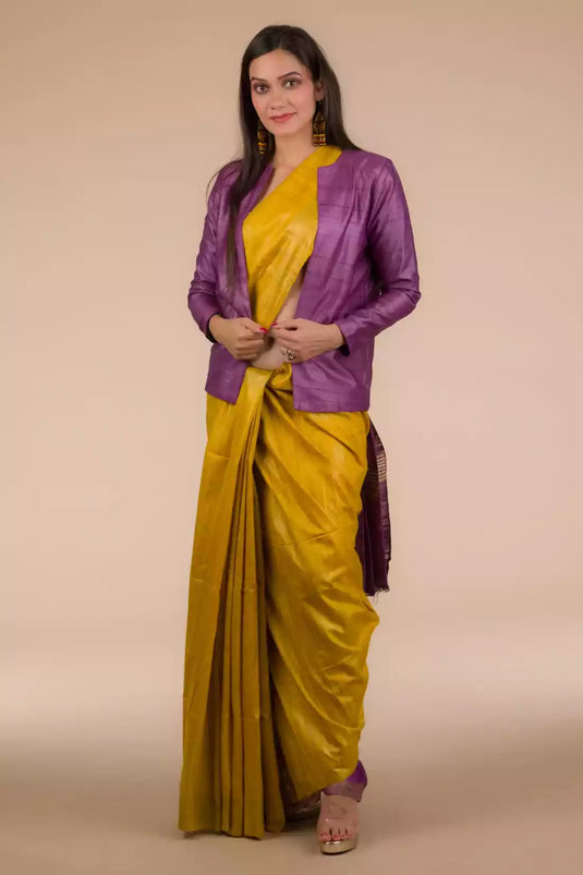 A lady in Mustard with purple border Plain In Pure Tussar with Ghicha Border Saree standing against a beige background.