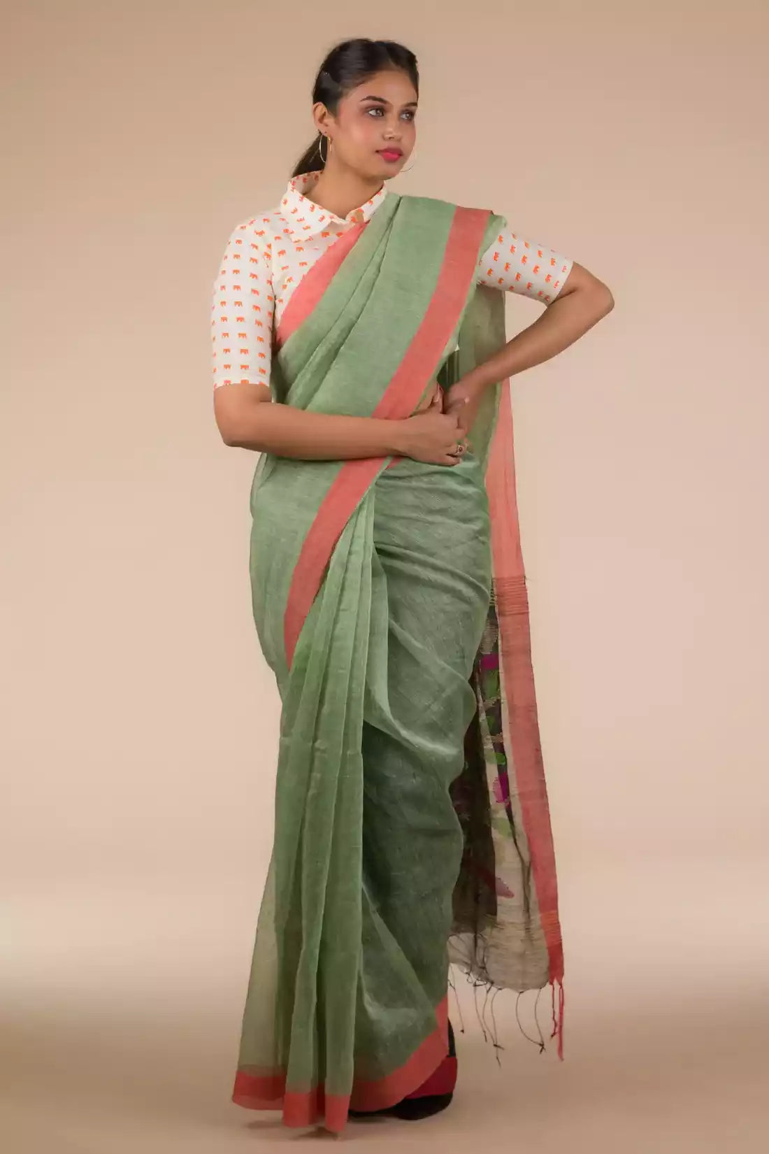 A lady in Pista green with jamdani pallu In Silk Linen Saree standing against a beige background.