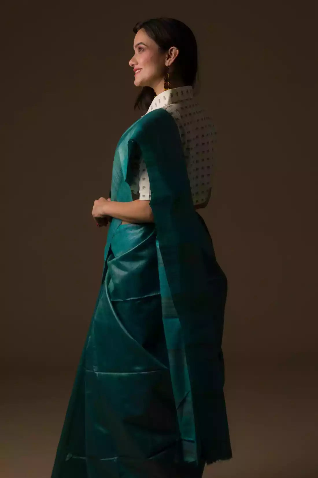 a woman looking sideways wearing formal workwear for women which is Sea green Plain In Pure Tussar Saree