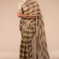 a woman in ethnic posing wearing brown & beige checks saree with tie top blouse and heels