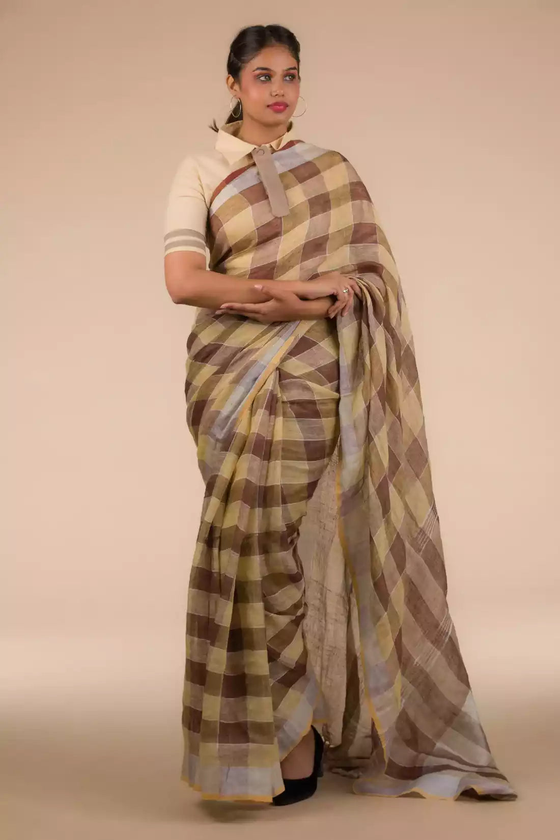 a woman in ethnic posing wearing brown & beige checks saree with tie top blouse and heels