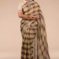 side view of a woman in ethnic posing wearing brown & beige checks saree with tie top blouse and black heels