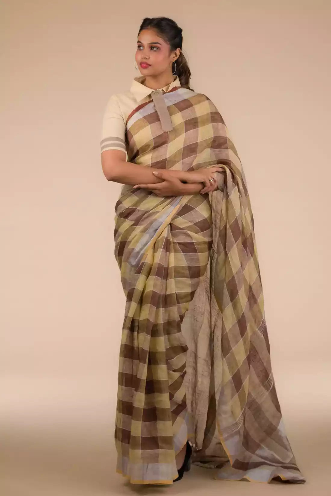 side view of a woman in ethnic posing wearing brown & beige checks saree with tie top blouse and black heels