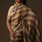 closure side view of a woman in ethnic posing wearing brown & beige checks saree with tie top blouse