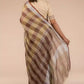 back view of a woman in ethnic posing wearing brown & beige checks saree with tie top blouse, flaunting loose end of her saree