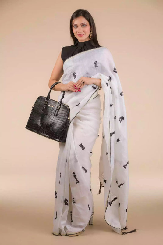 A model in Indyvarna’s Exclusive Ivory White Linen Silk Saree with Hand Embroidery a womens workwear is standing  against a beige background