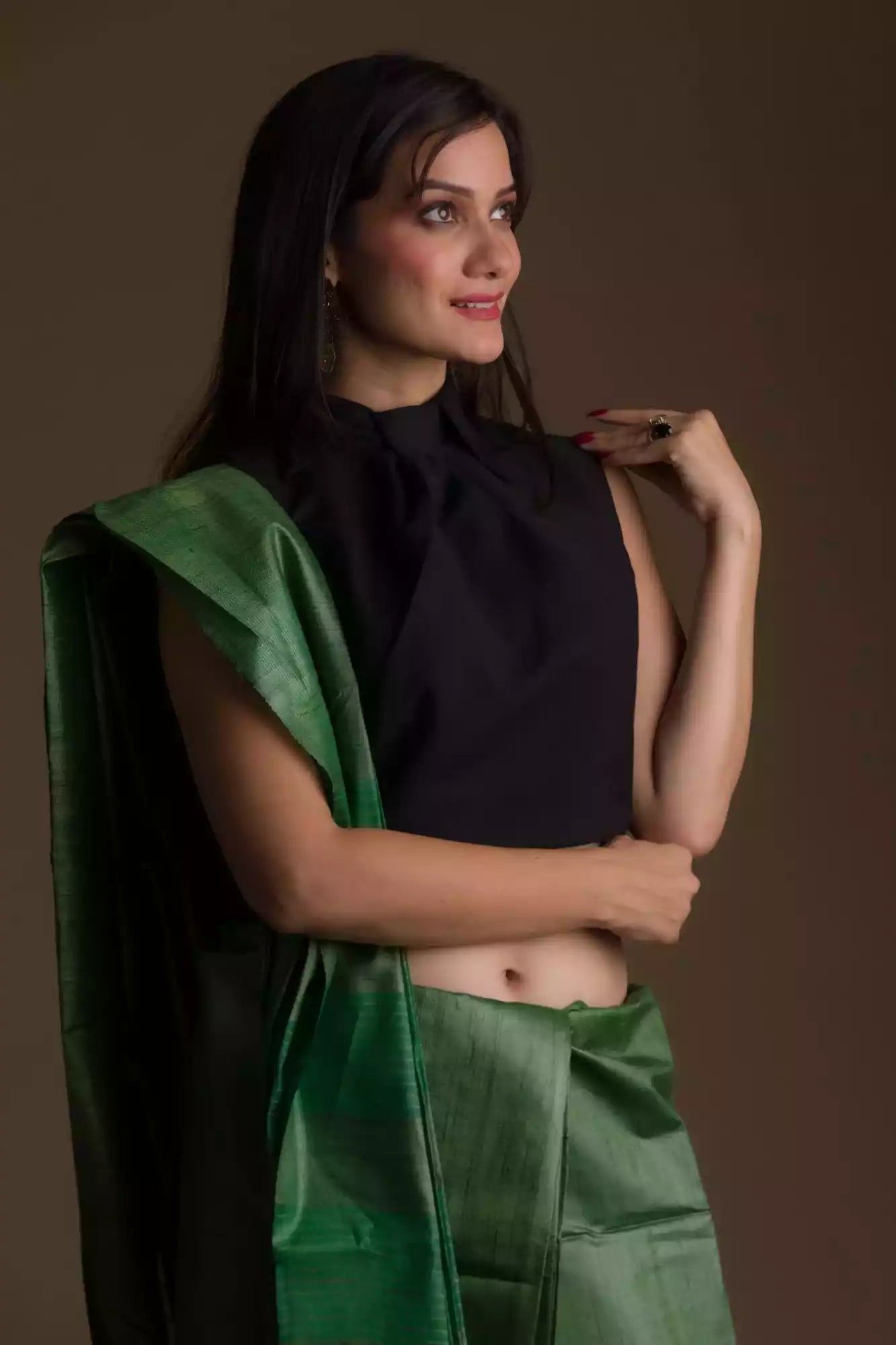 side view of a woman in ethnic posing wearing dark green saree with black blouse