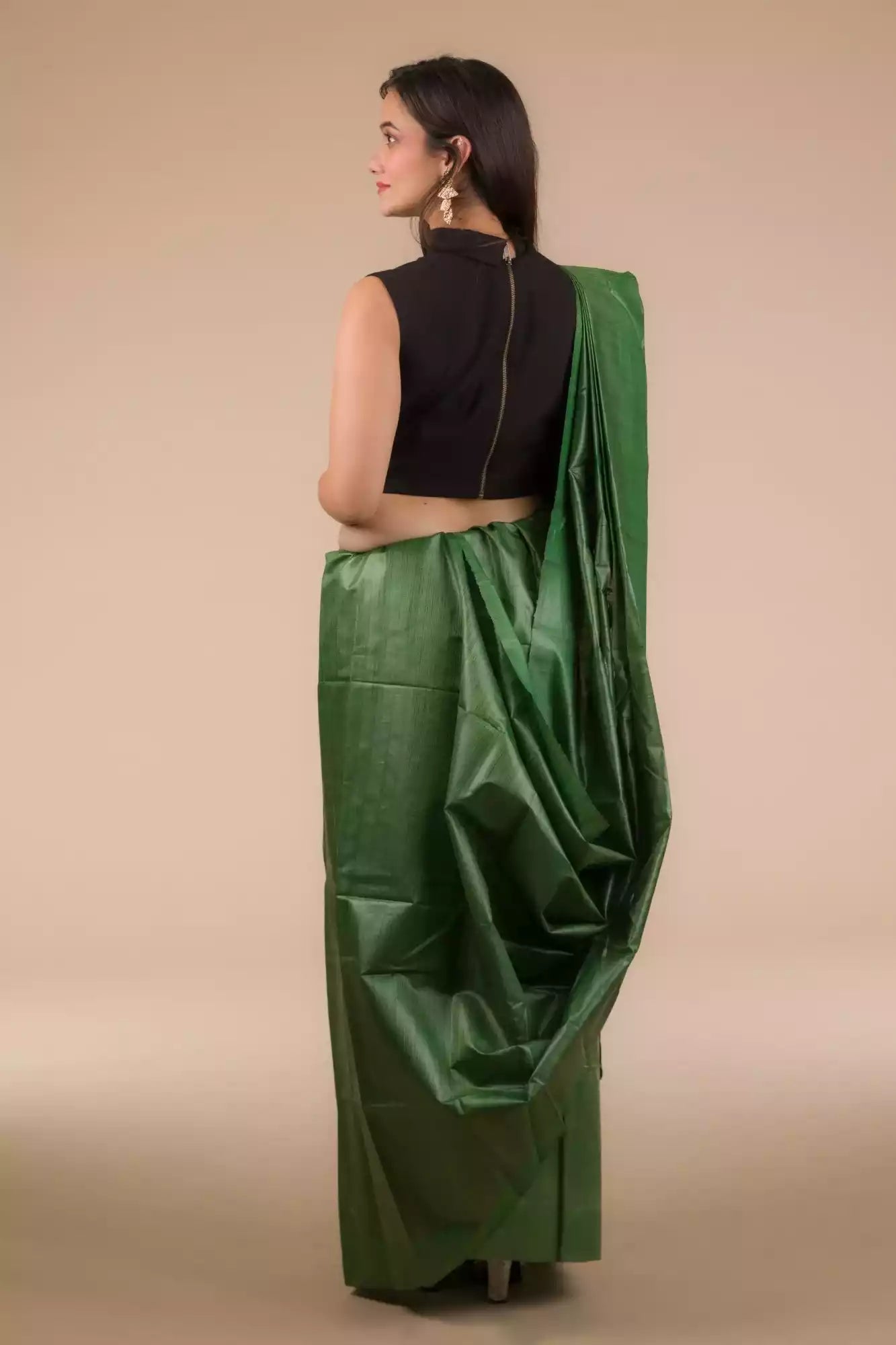 back view of a woman in ethnic posing wearing dark green saree with black blouse and heels