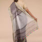 back view of a woman posing in an ethnic grey saree with tie top blouse, flaunting loose end of her saree