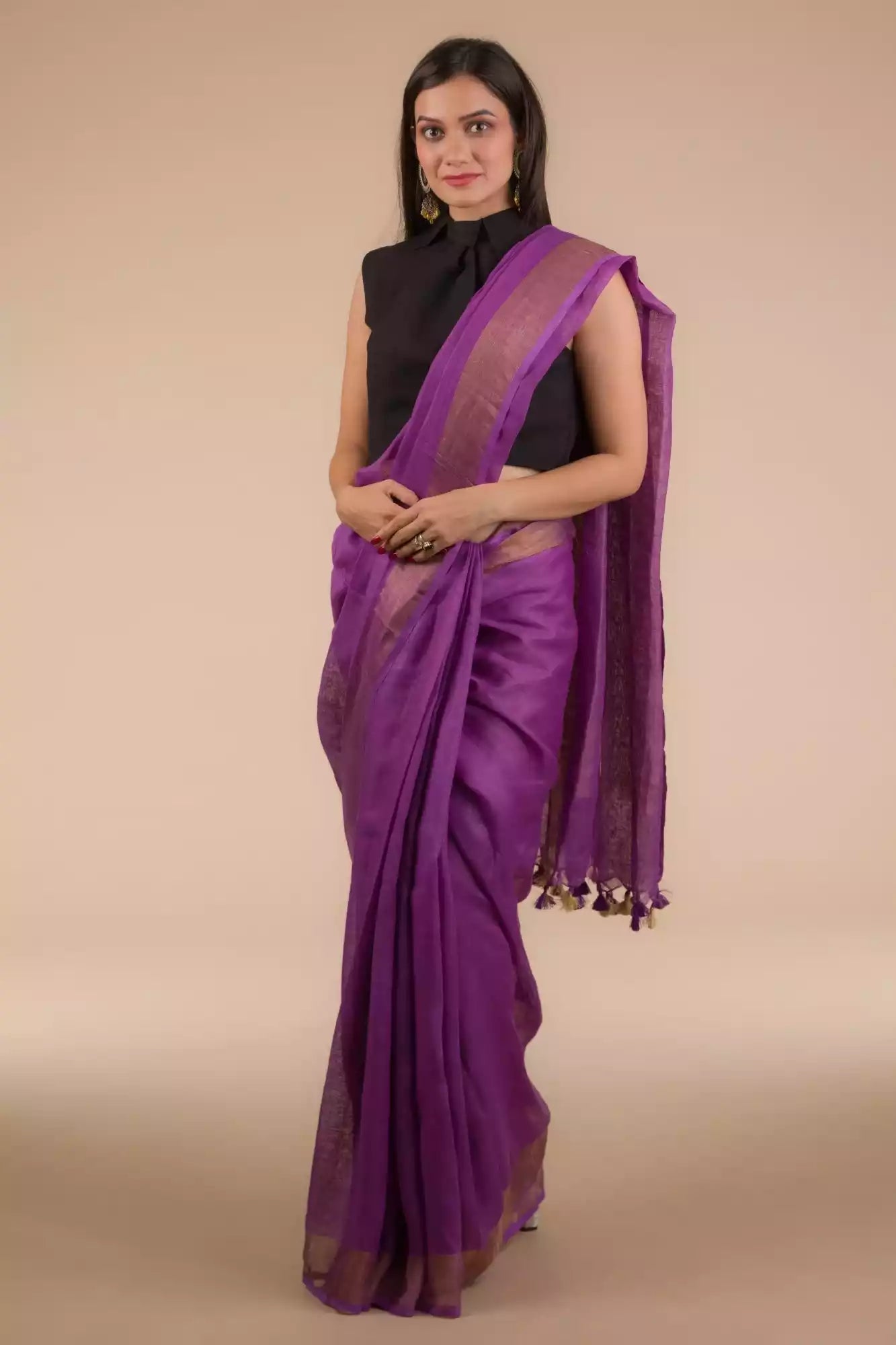 a woman wearing a purple saree with black blouse and gold accents on the border