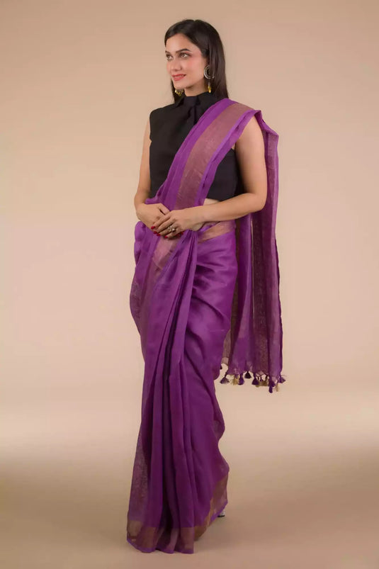 side view of a woman wearing a purple saree with black blouse and gold accents on the border