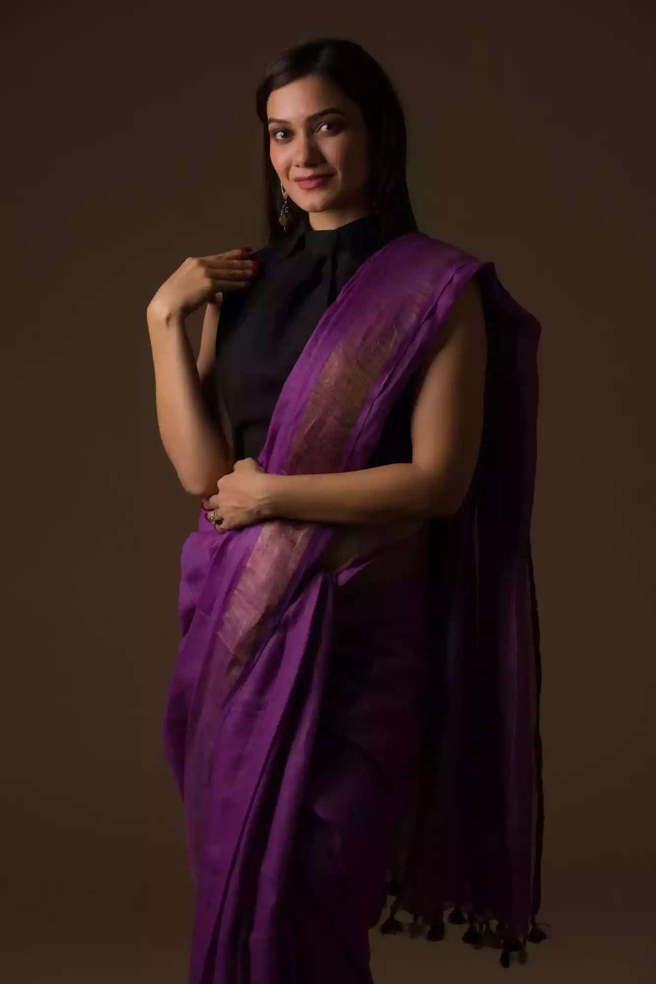front view of a woman wearing a purple saree with black blouse and gold accents on the border