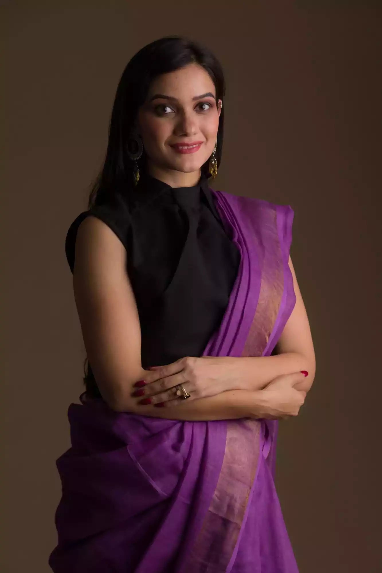 a beautiful woman wearing a purple saree with black blouse and gold accents on the border, and hands being folded