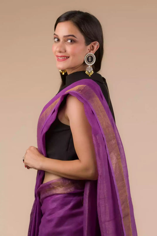 a beautiful woman looking sideways wearing a purple saree with black blouse and gold accents on the border