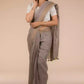 A lady in Fossil Grey Plain in Pure Linen Saree standing against a beige background.