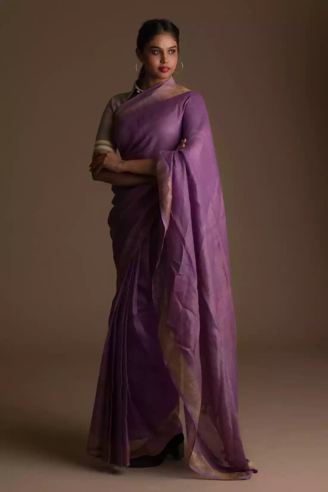A lady in Mauve Bloom Linen Saree in Dark Purple, womens workwear standing against a tan background looking  down