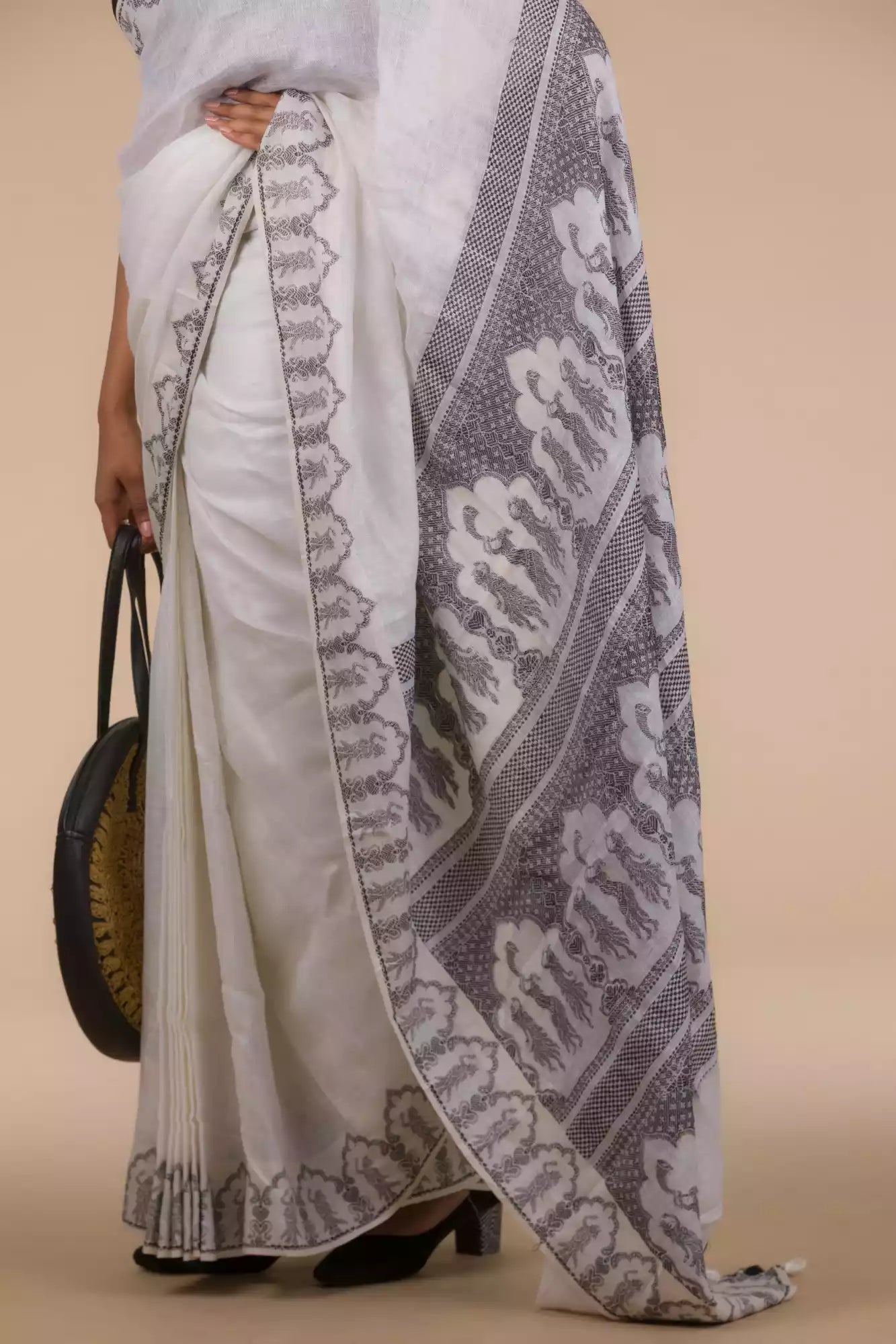 A picture of  Baluchari Resham Thread Linen Saree in White, womens workwear standing against a beige background 