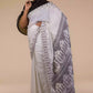 A lady in Baluchari Resham Thread Linen Saree in White, womens workwear standing against a beige background looking sideways