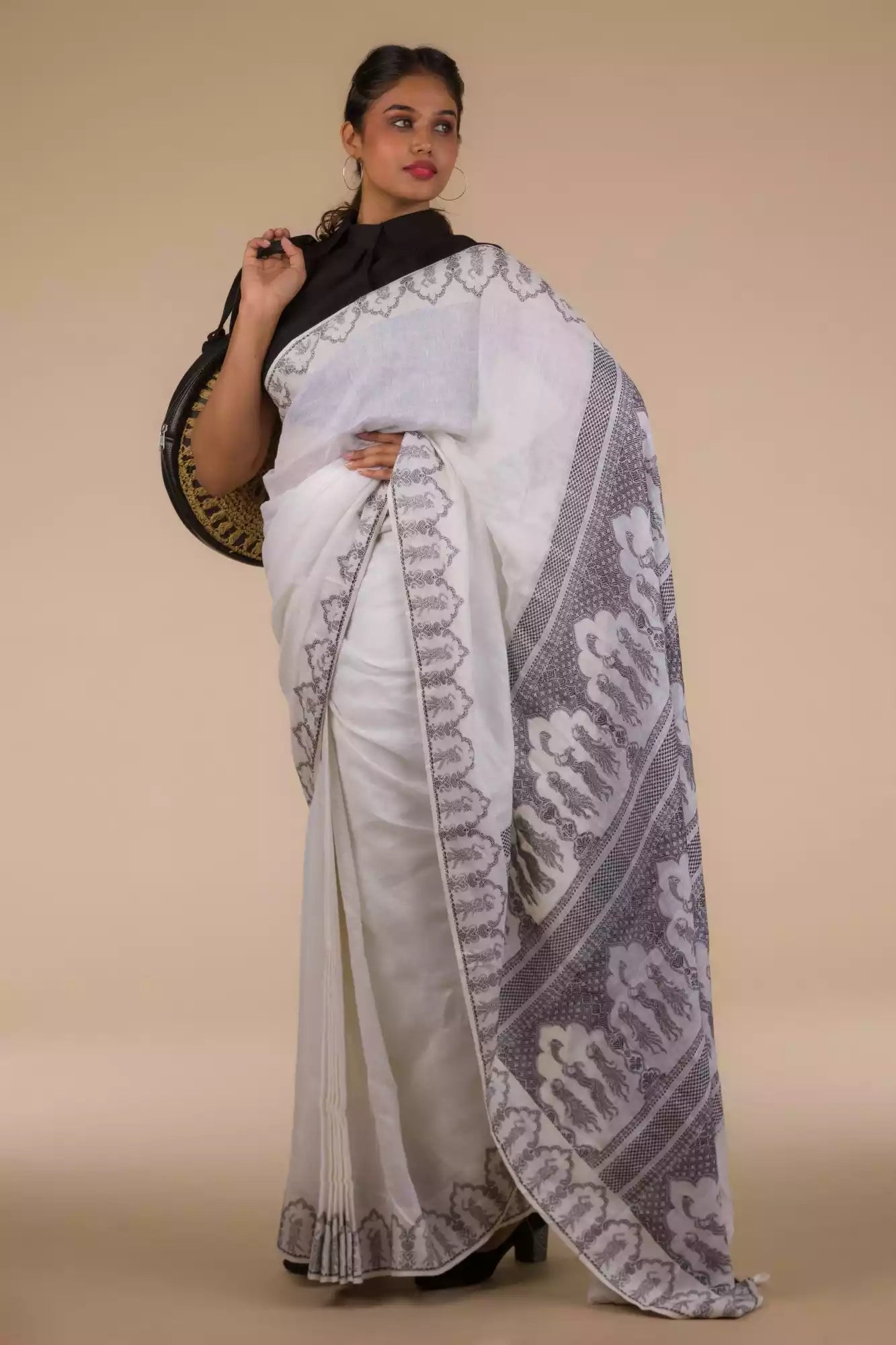 A lady in Baluchari Resham Thread Linen Saree in White, womens workwear standing against a beige background looking sideways