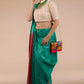 A lady in Sea Green and Red Border Plain In Pure Tussar with Ghicha Border Saree standing against a beige background