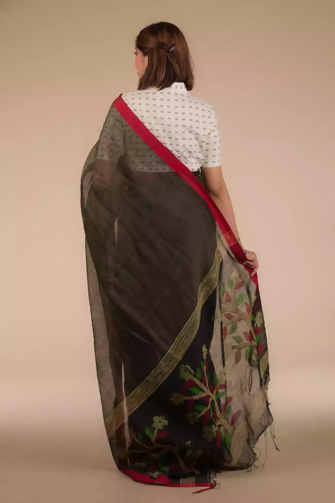 back view of a beautiful woman with short hair wearing a chocolate brown saree with collared blouse, flaunting loose end of her saree