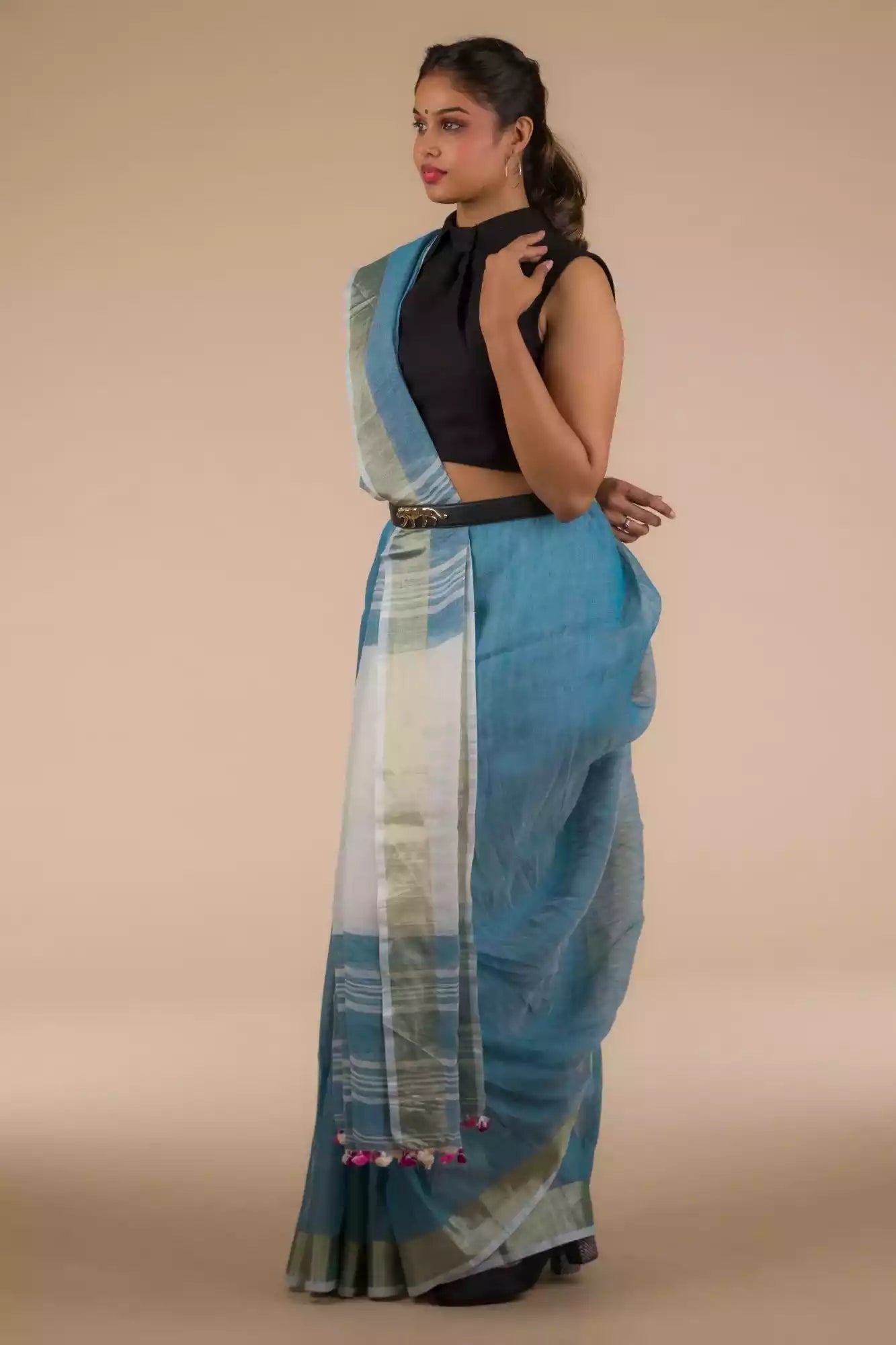 side view of a woman wearing a blue saree and a black blouse with stripes at the border and a belt