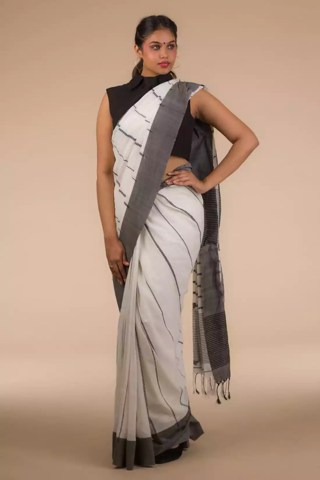Side view of a woman wearing white saree with black stripes on it
