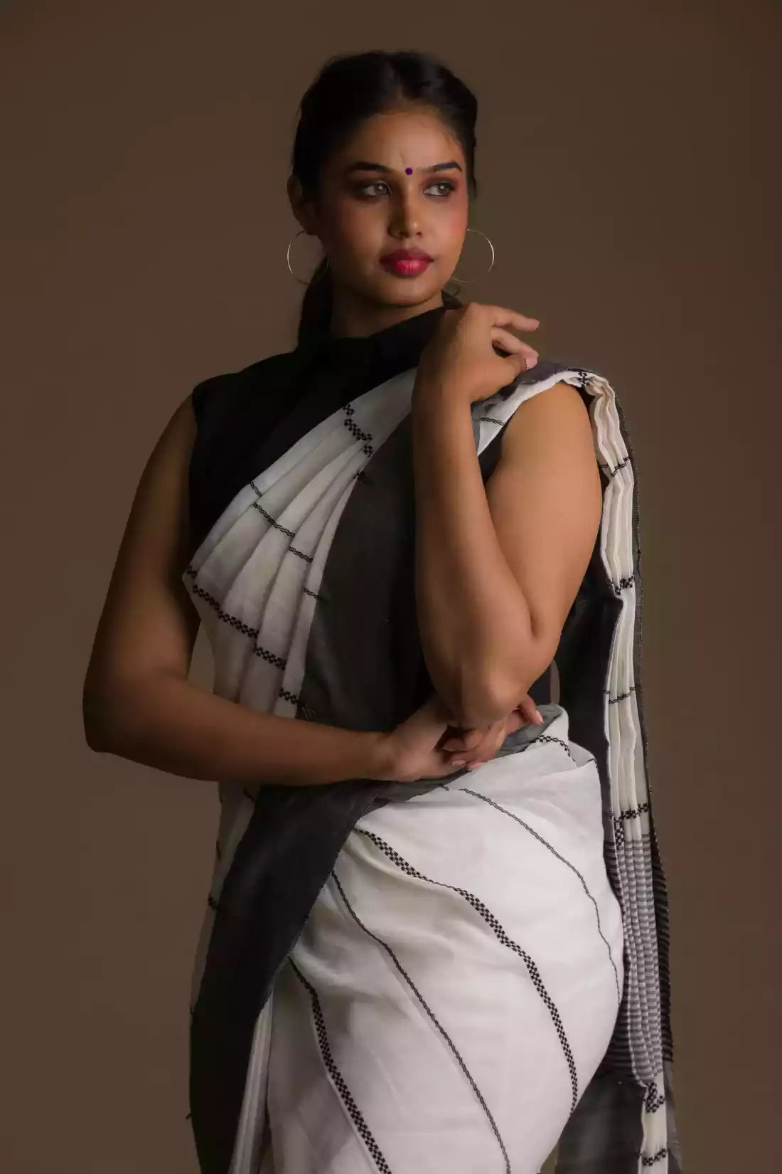 an attractive woman wearing white saree with black stripes on it