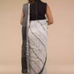 Back view of a woman wearing white saree with black stripes on it