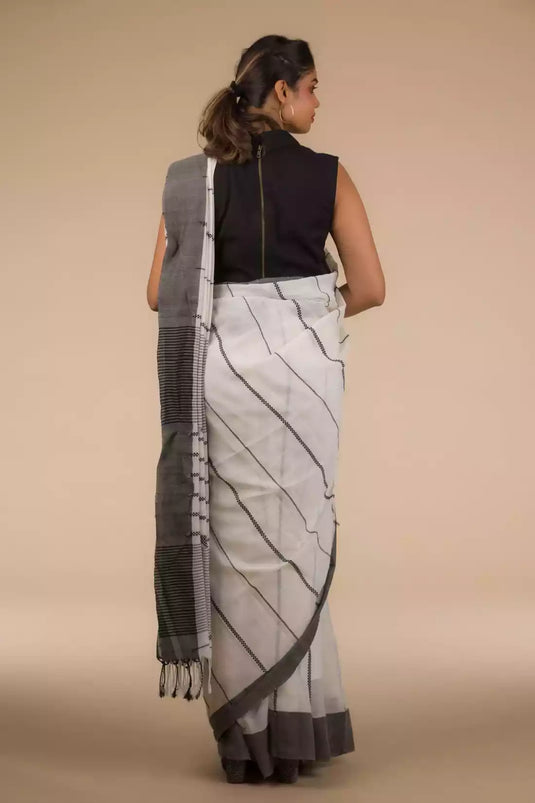 Back view of a woman wearing white saree with black stripes on it
