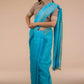 a woman wearing a cyan saree with brown blouse with her hands around her waist