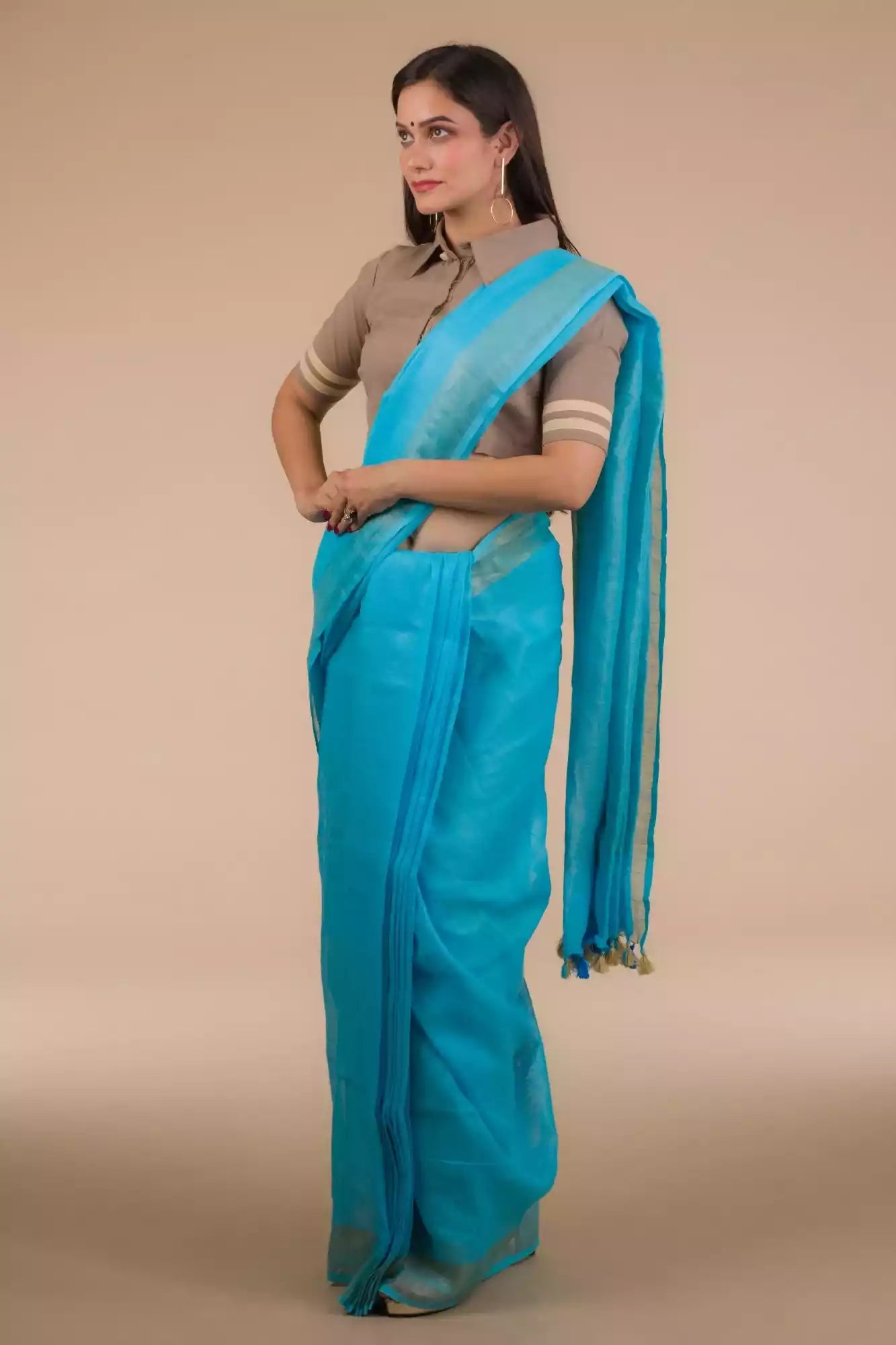 a woman wearing a cyan saree with brown blouse with her hands around her waist
